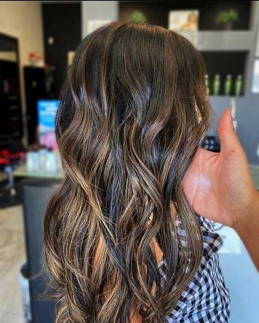 Long dark brown hair with caramel balayage in loose curls